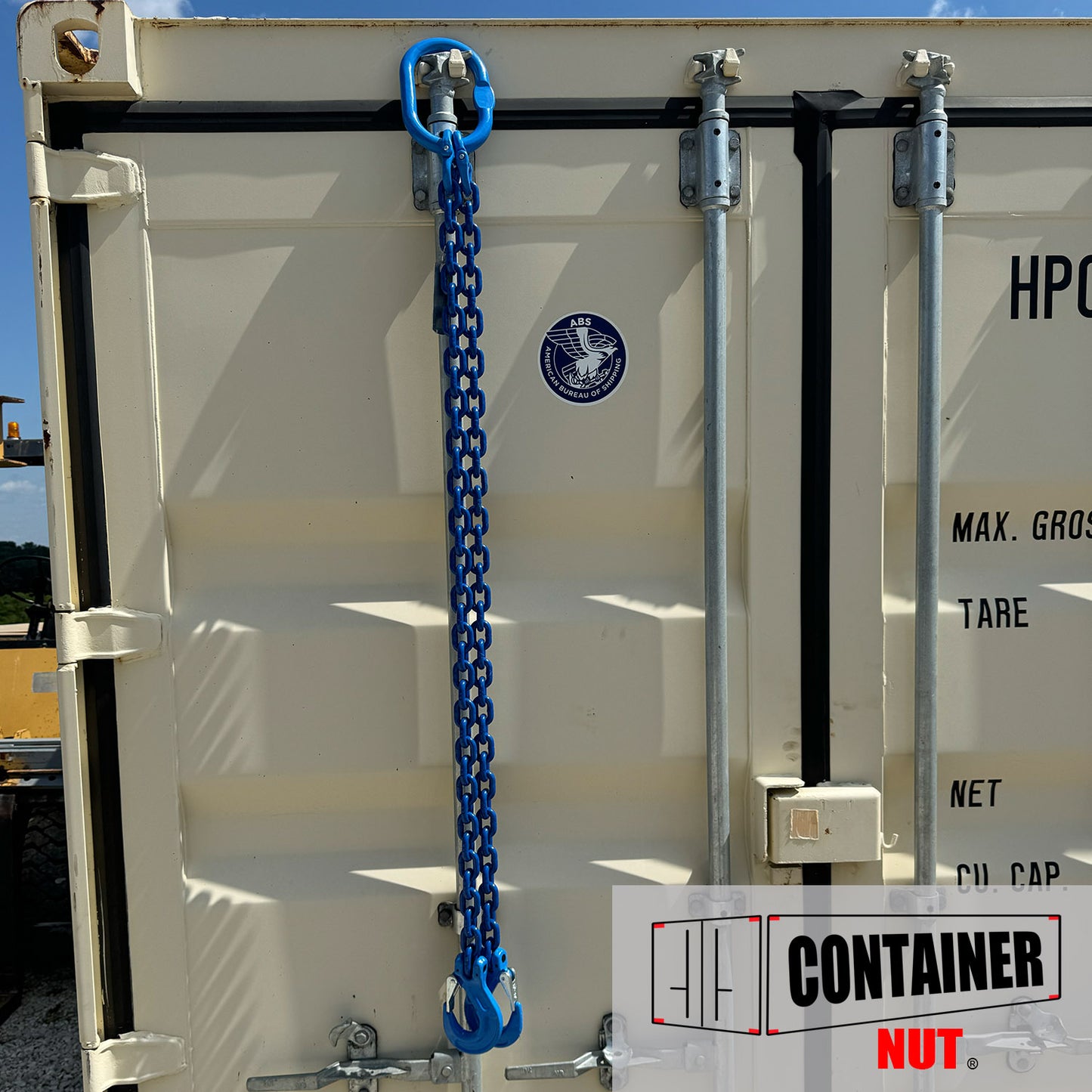 A white shipping container with metal fixtures on the door is secured with a Chain Sling. The container features a logo in the upper center labeled "HP" along with other specifications. In the bottom right corner, there's a logo for Container Nut.