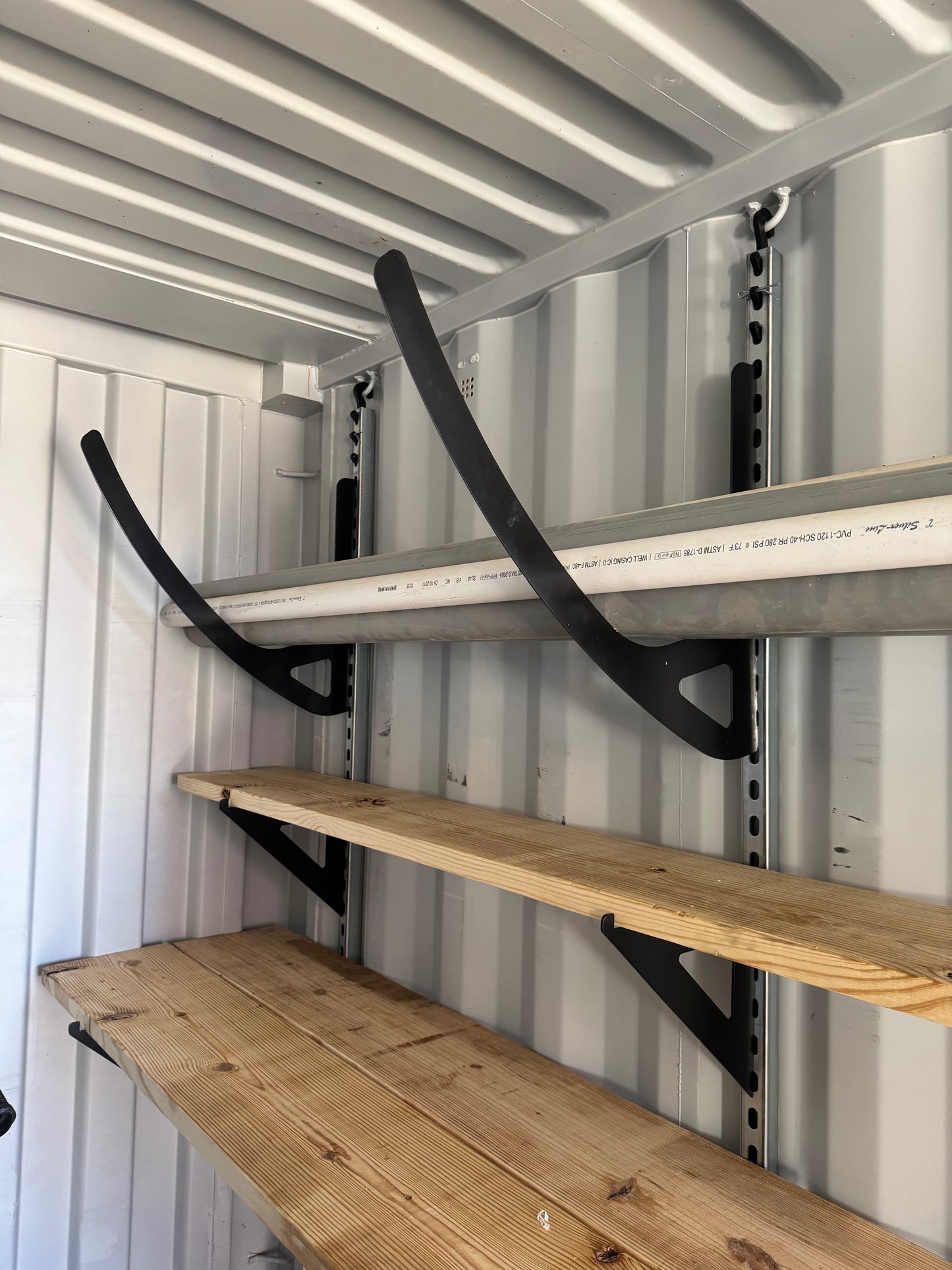 Wall-mounted brackets and wooden shelves inside a metal storage container